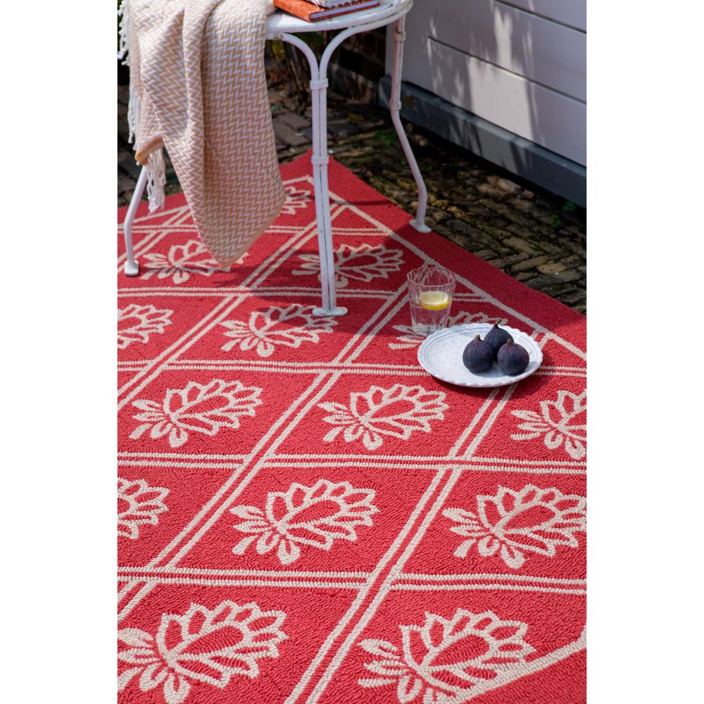 red floral outdoor rug in backyard with chair and throw - House