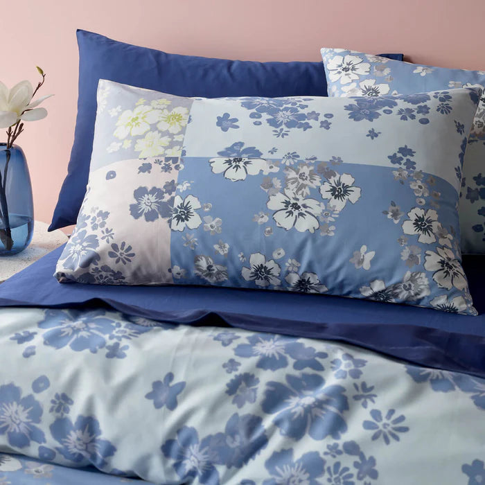 Floral patterned bedding set with blue and white flowers on a pink wall background