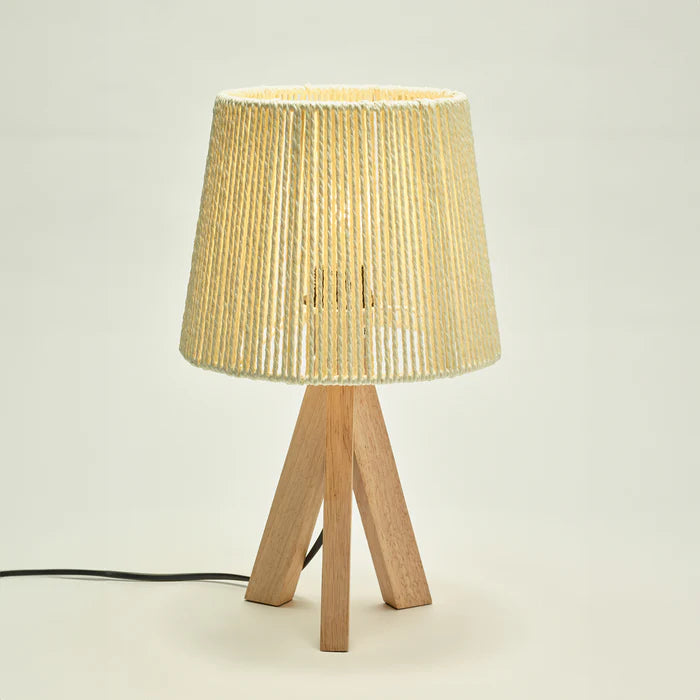 Table lamp with a woven shade and wooden base on a light background
