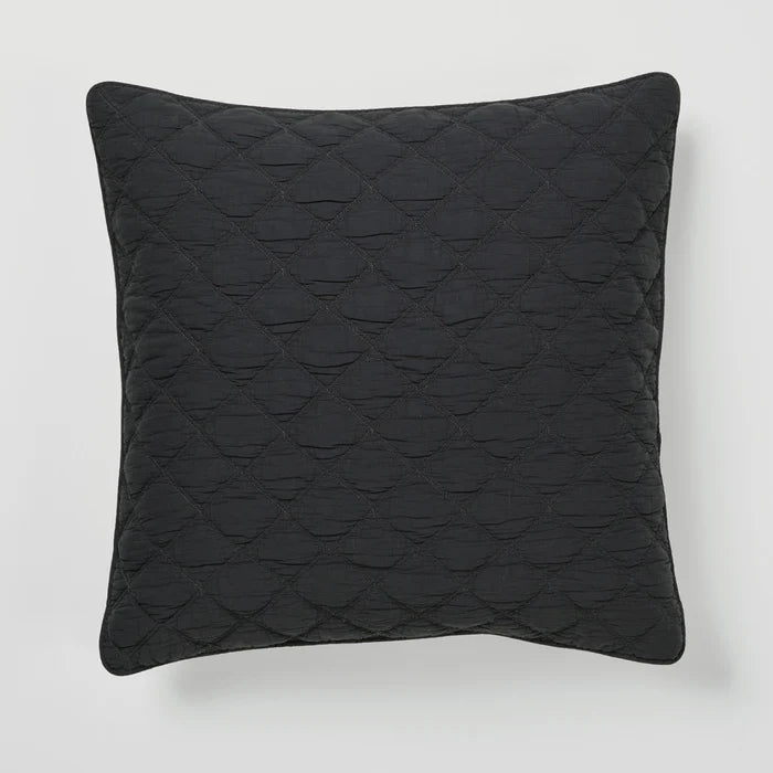 Black quilted pillow on a light gray background