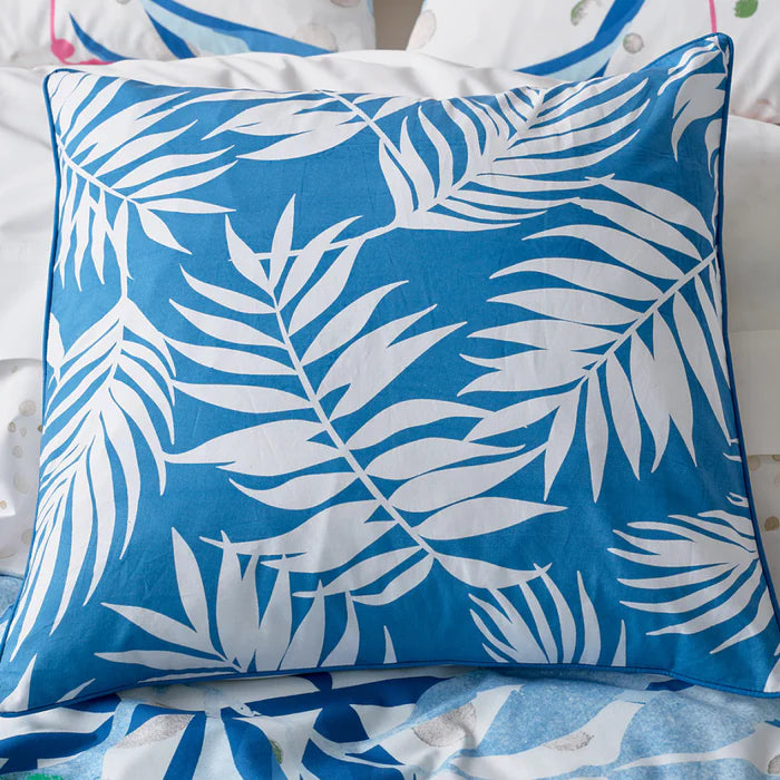 Blue pillow with white leaf pattern on a bed