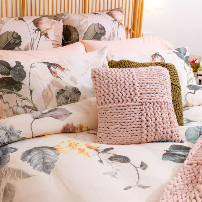 Floral bedding with pink knitted pillow and green blanket
