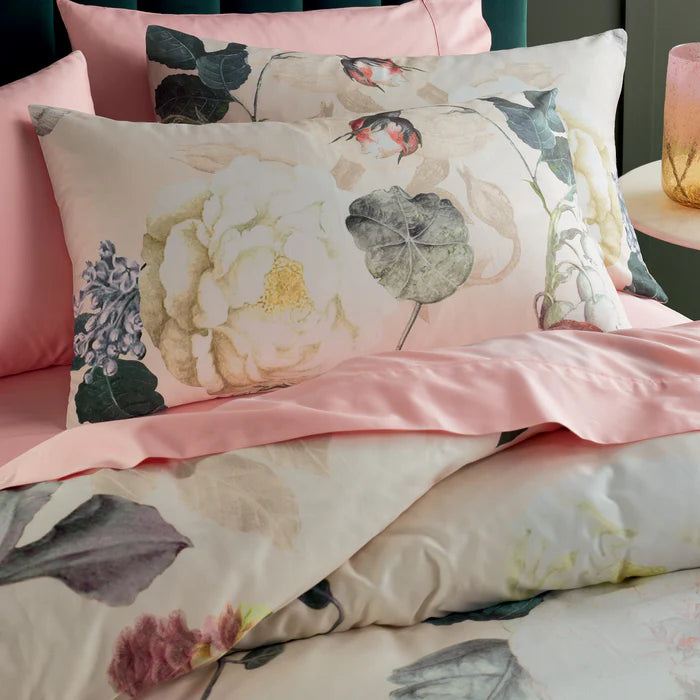 Floral and leaf patterned bedding set with pink accents on a bed.
