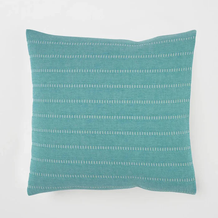 Teal pillow with white stripes on a light gray background