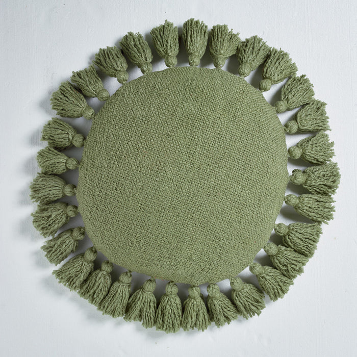 Green round knitted mat with tassels on a light gray background
