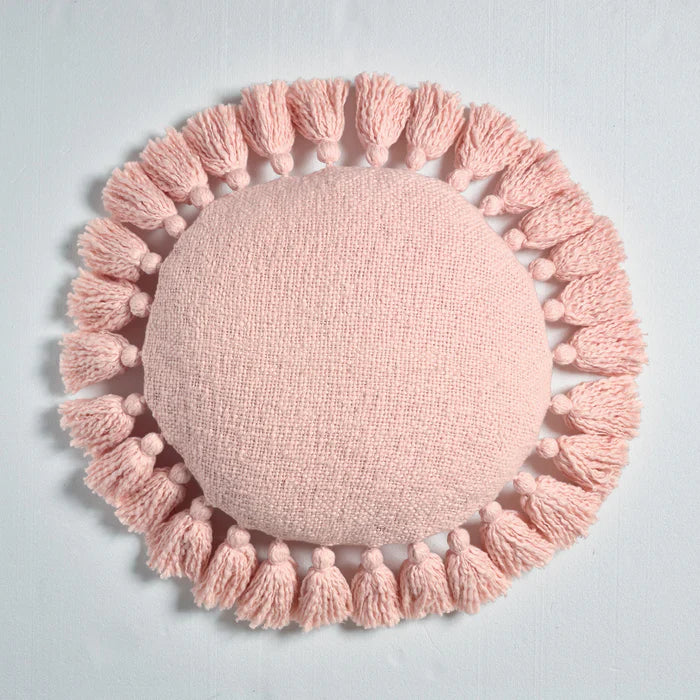 Pink round pillow with tassels on a light gray background