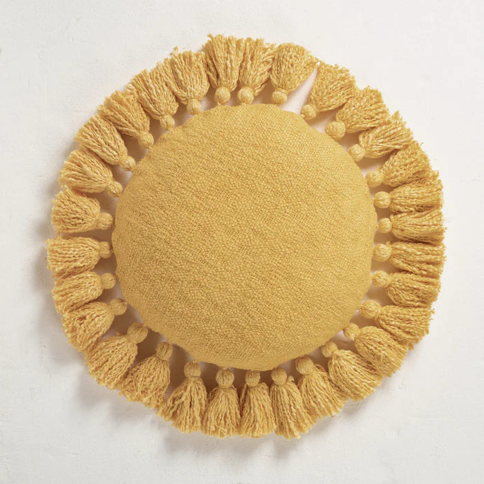 Round yellow pillow with tassels on a light gray background
