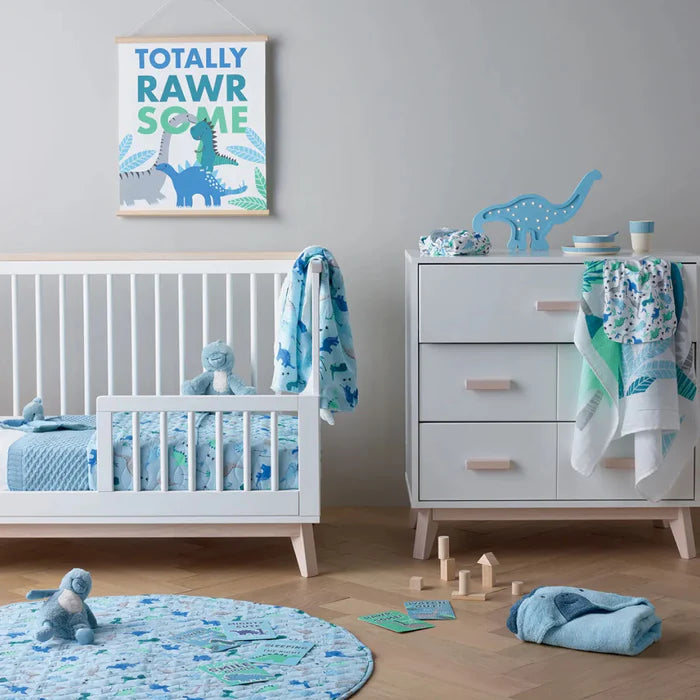 Nursery room with white crib, dresser, and dinosaur-themed decor.