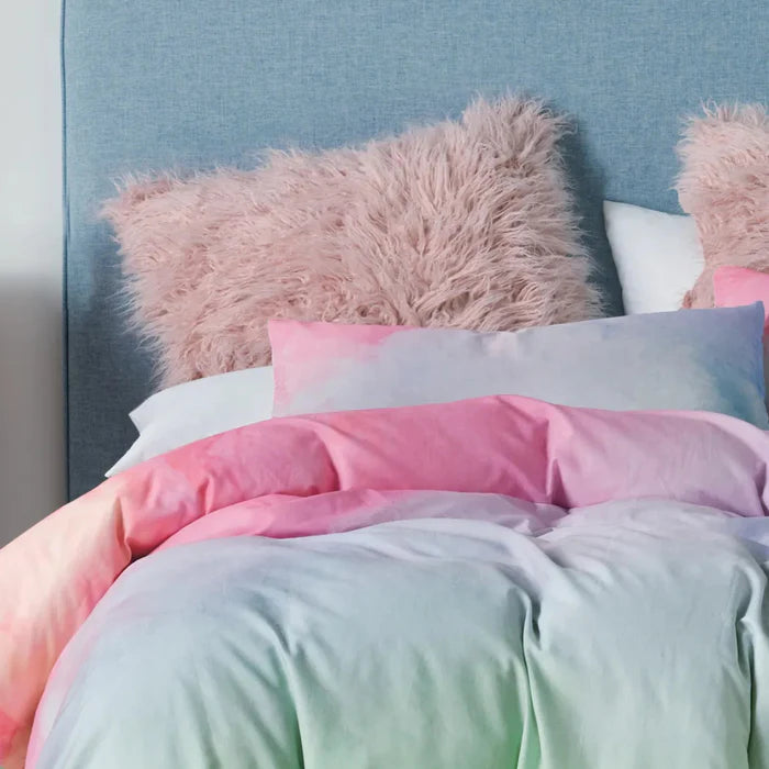 Pastel-colored bedding with fluffy pink pillows on a bed.