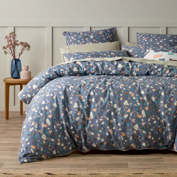 Floral patterned bedding set on a bed with a wooden headboard and side table.