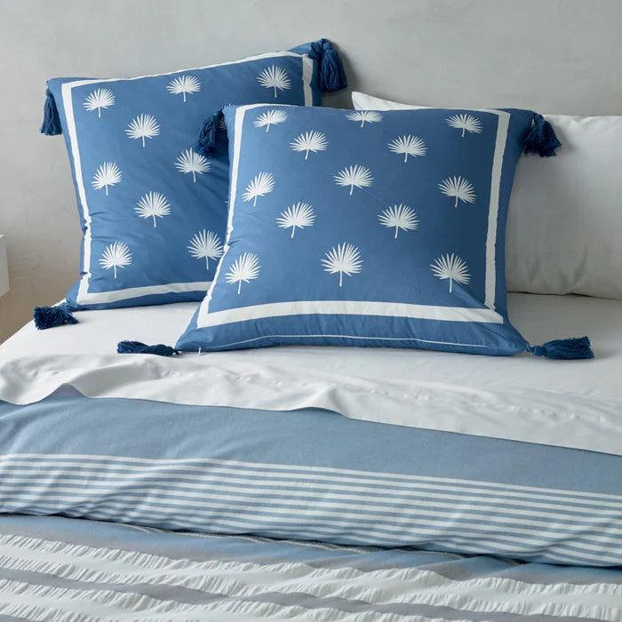 Blue and white patterned pillows on a bed with striped bedding.