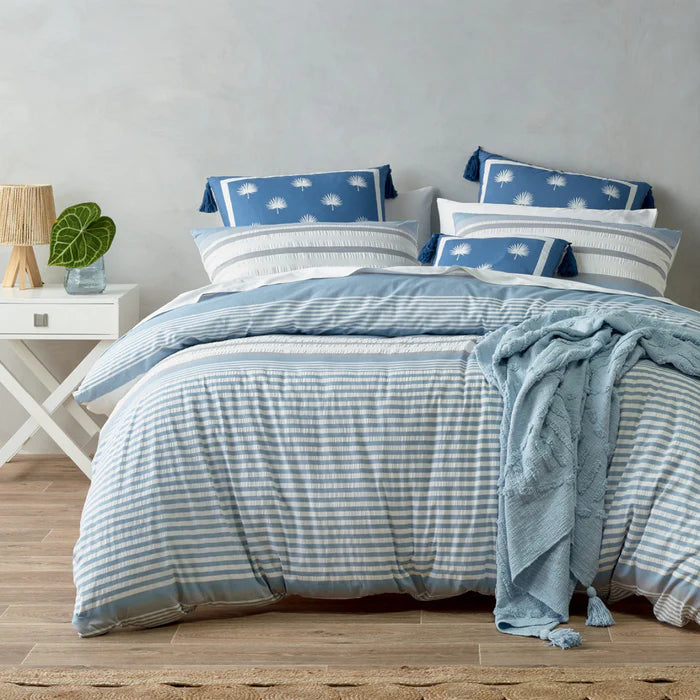 Bed with blue and white striped bedding in a bedroom setting.