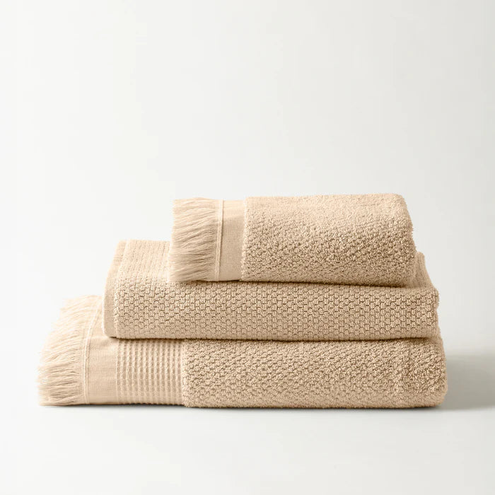 Beige towels stacked on a light gray background