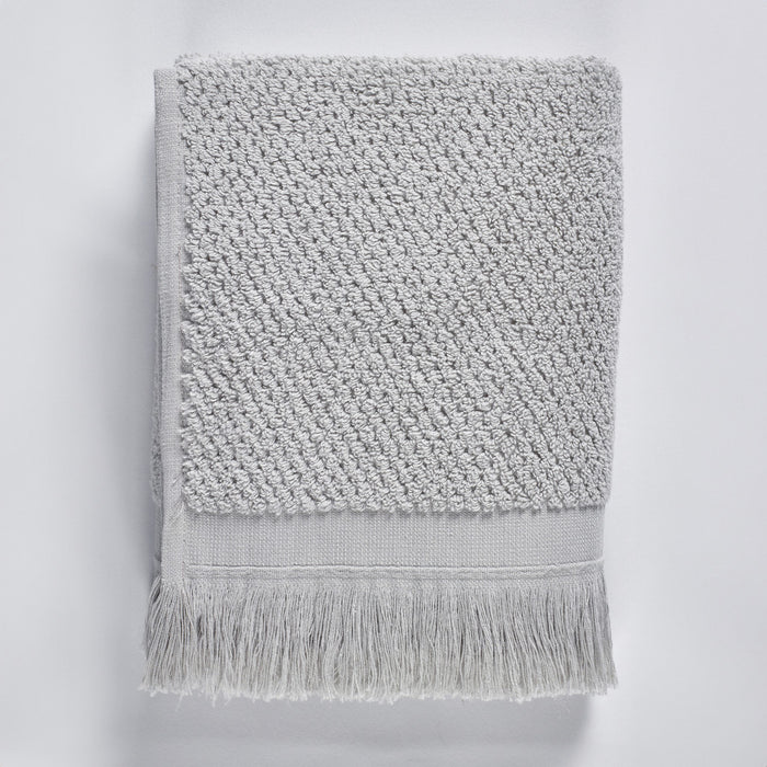 Gray textured bath towel with fringes on a light gray background