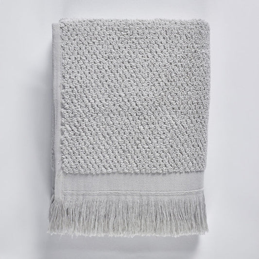 Gray textured bath towel with fringes on a light gray background