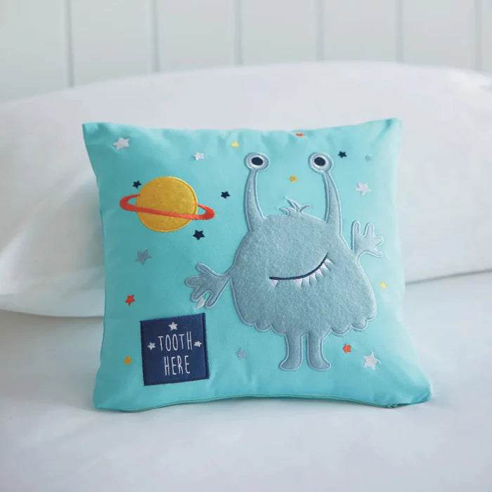 Children's pillow with a cartoon monster design on a white couch.