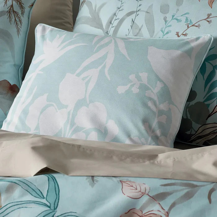 Floral patterned bedding with light blue and beige pillows.
