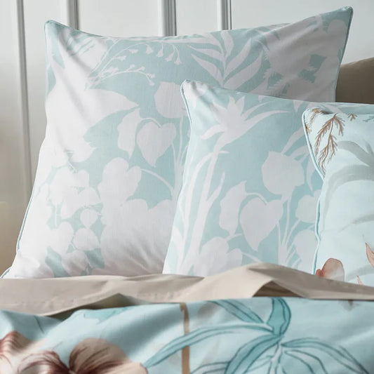 Floral patterned pillows and bedspread on a bed with a neutral background