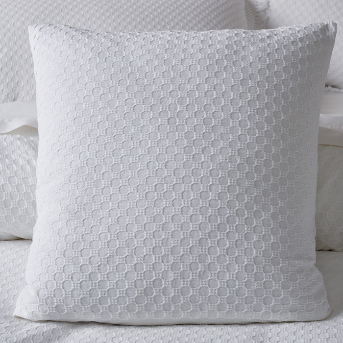 Gray textured pillow on a bed with white bedding
