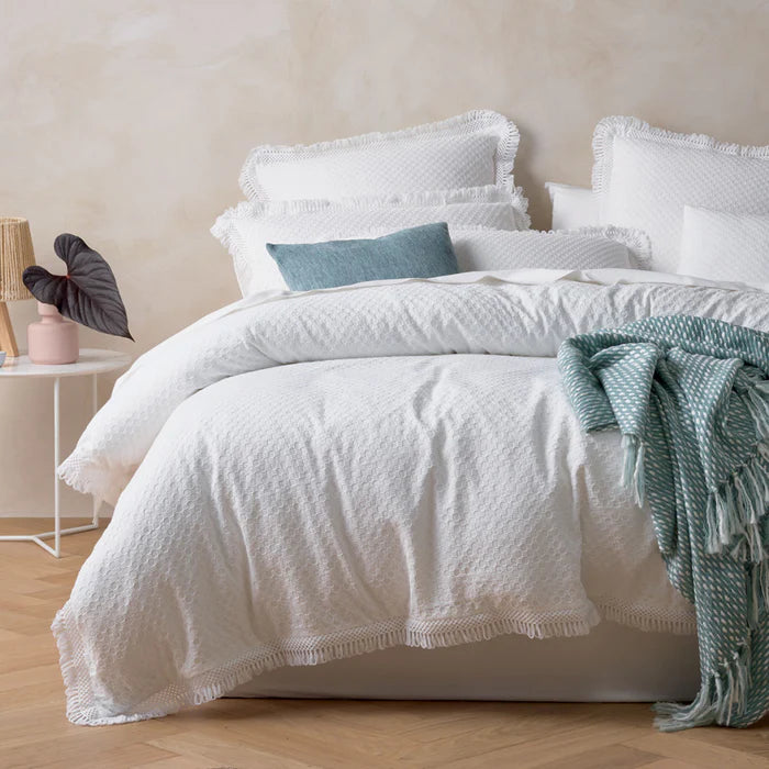 Neatly made bed with white bedding and a green throw blanket in a bedroom setting.