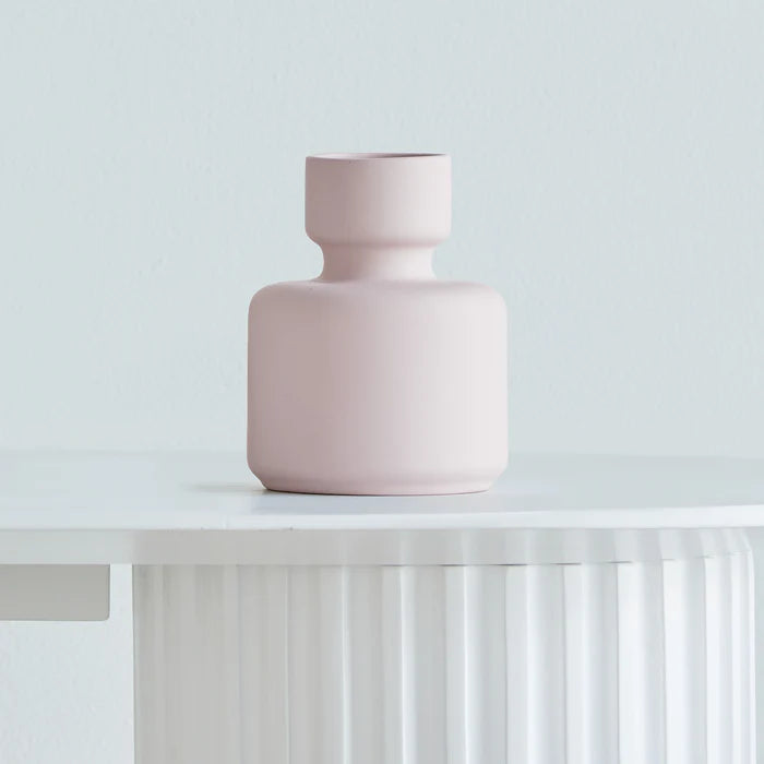 Pink vase on a white surface with a light gray background