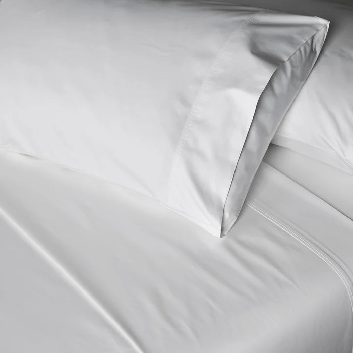 Close-up of light gray bedding with a pillow and duvet.