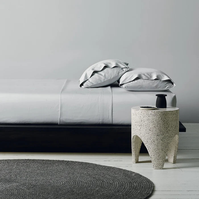 Modern bedroom with a bed, side table, and decorative items.