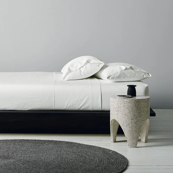 Modern bedroom with a bed, side table, and rug.