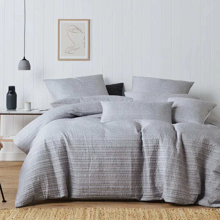 Gray textured bedding set on a bed in a bedroom with a white wall and framed art.
